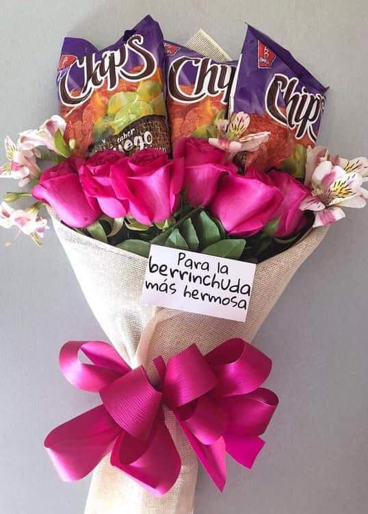 a bouquet of flowers with candy bars wrapped in pink ribbon