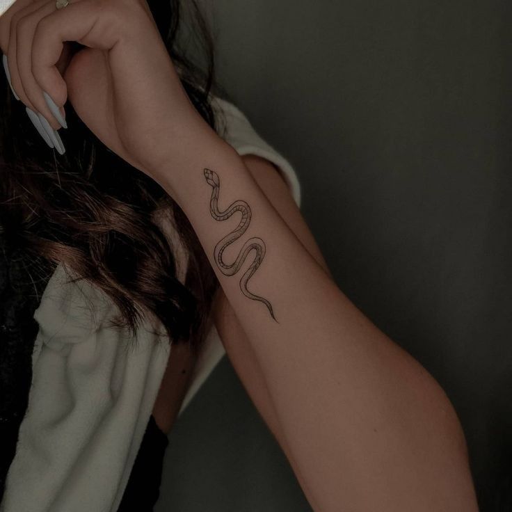 a woman's arm with a snake tattoo on the left side of her arm