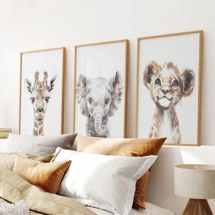 three framed giraffes are hanging on the wall above a bed with pillows