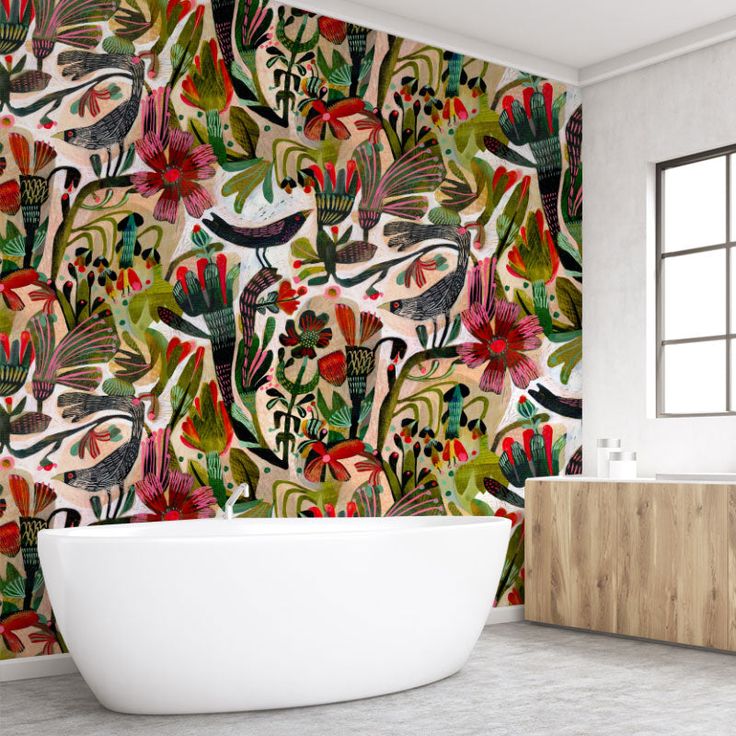 a bath tub sitting next to a wall covered in colorful flowers and birds on it