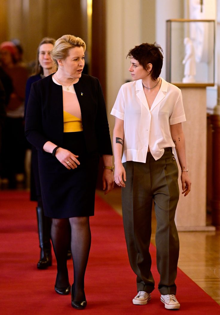 two women walking down a red carpeted hallway next to each other in business attire