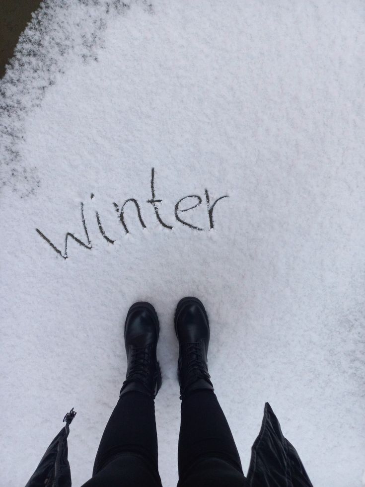 someone is standing in the snow with their feet up and writing winter on the ground