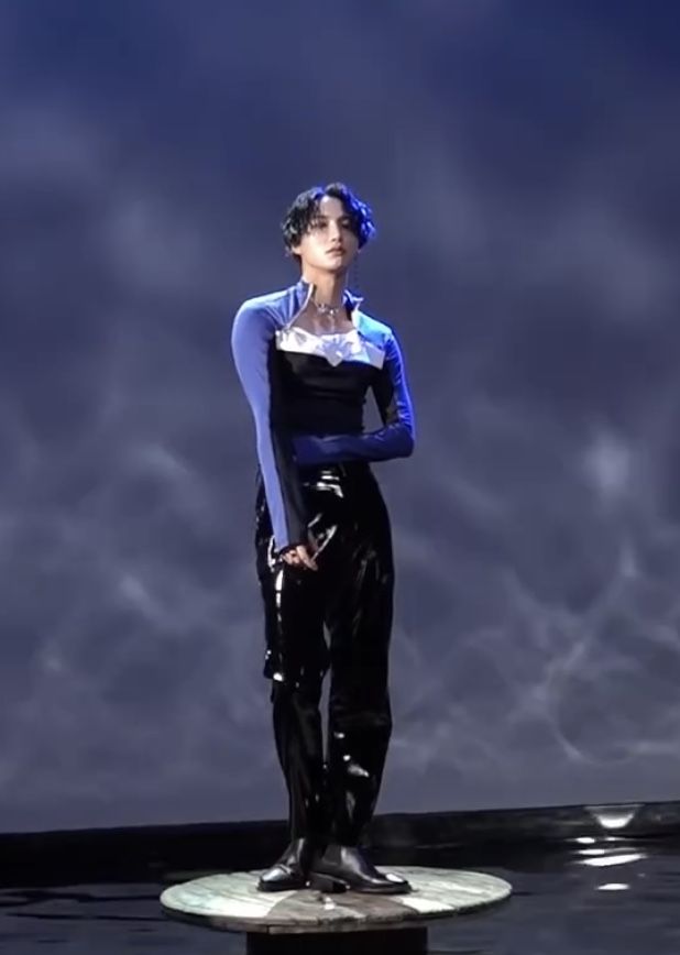 a woman in black and blue is standing on a pedestal