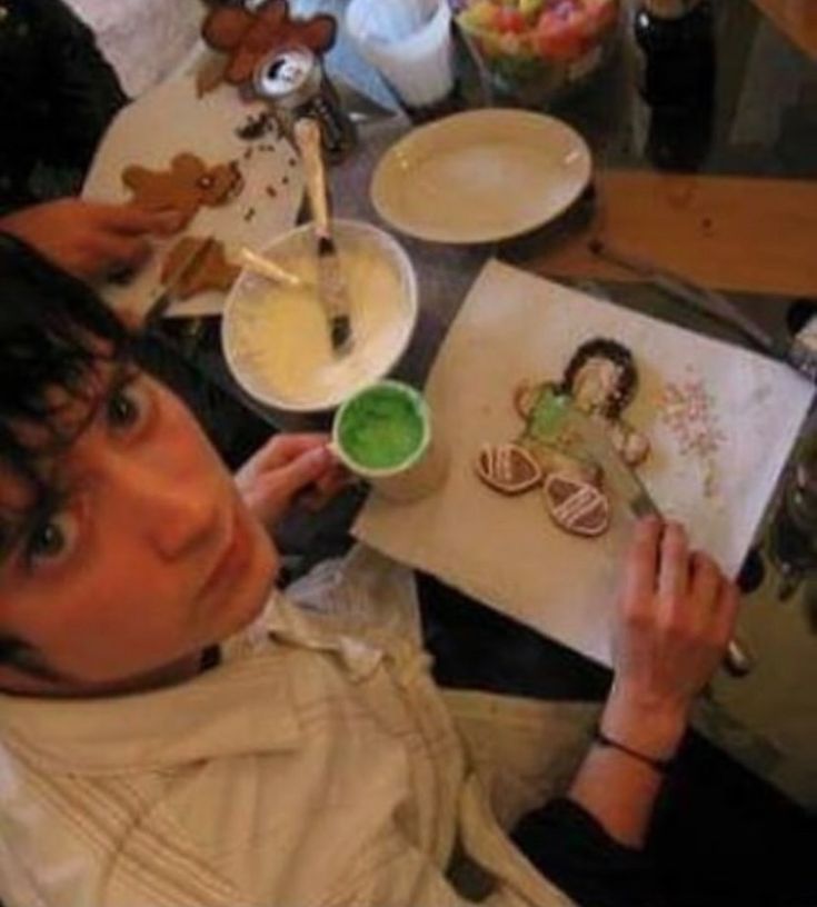 a woman sitting at a table with some cookies and green liquid in front of her