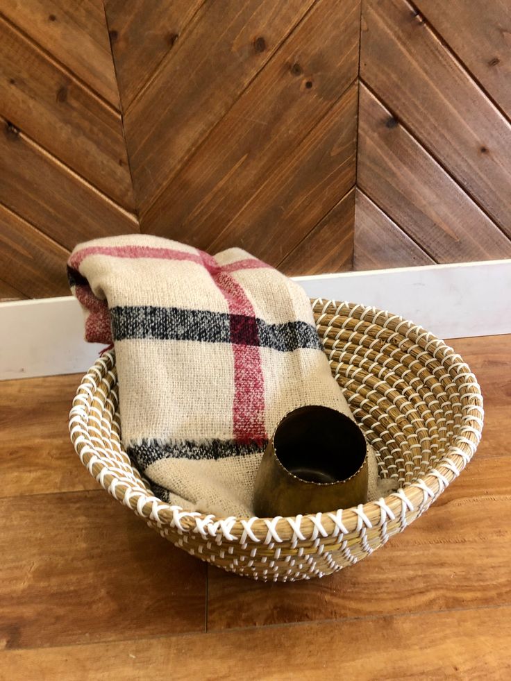 a woven basket with a plaid pillow on the floor