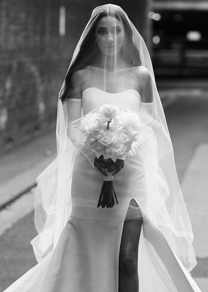 black and white photograph of a bride walking down the street with her bouquet in hand