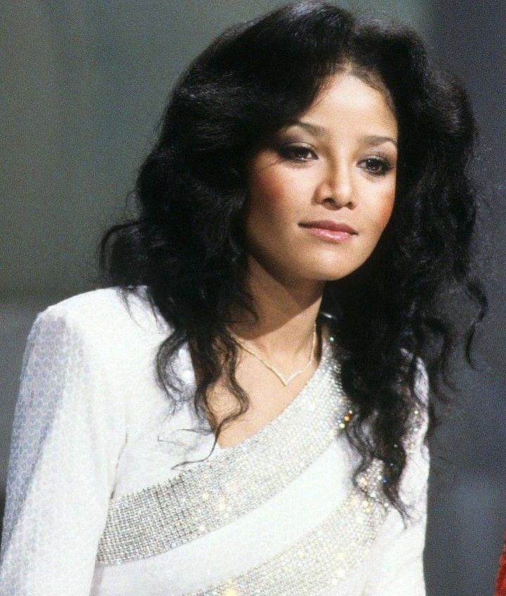 a woman with long black hair wearing a white dress