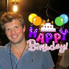 a man standing in front of a birthday cake with balloons on it and the words happy birthday