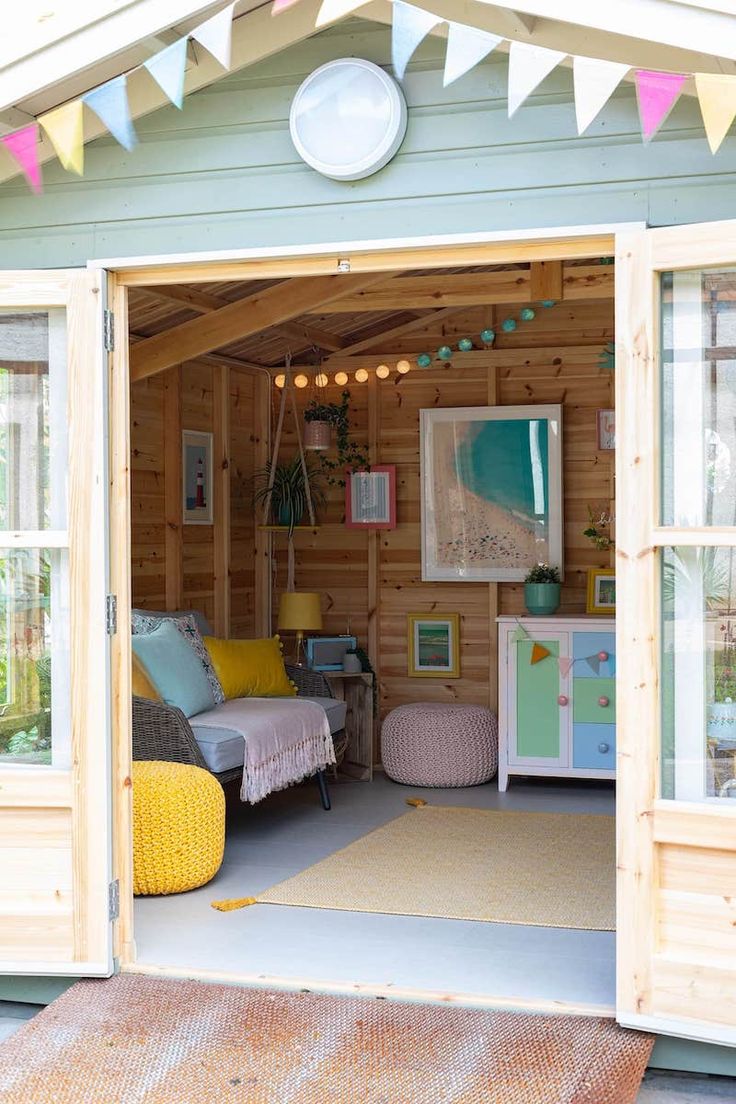 the inside of a small wooden shed with two chairs and a couch in front of it