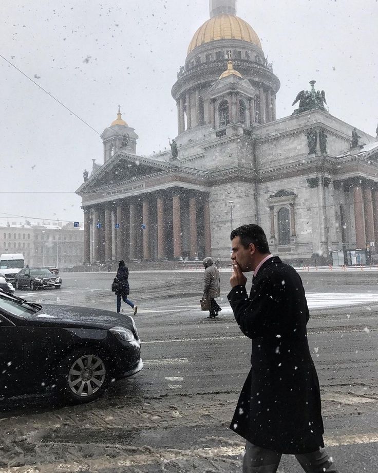 a man walking down the street while talking on a cell phone in front of a large building