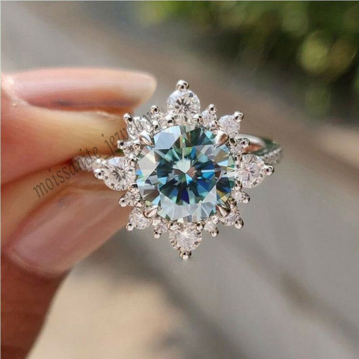 a woman's hand holding a blue and white diamond ring