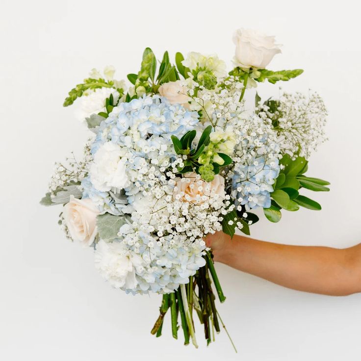 a person holding a bouquet of white and blue flowers