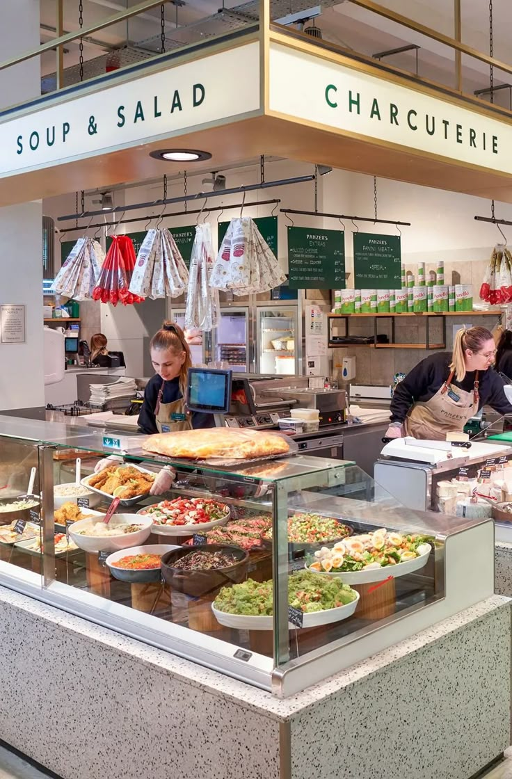 people are standing in line at the counter of a restaurant with lots of food on it