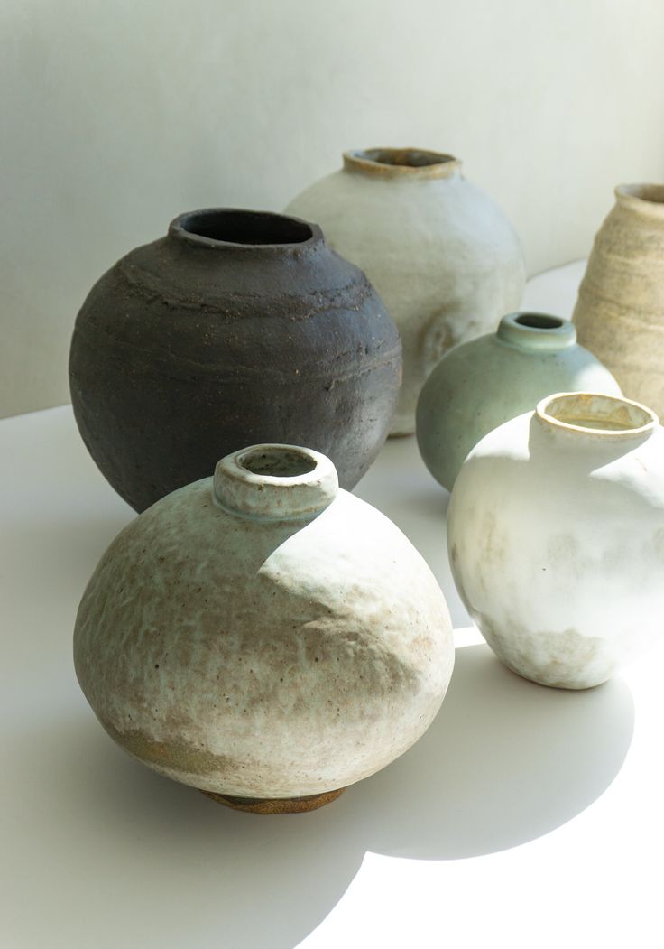 five vases sitting on top of a white table