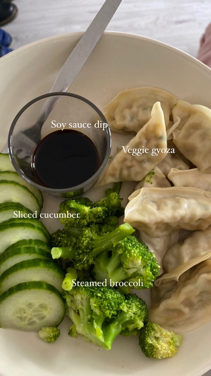 a white plate topped with dumplings and broccoli