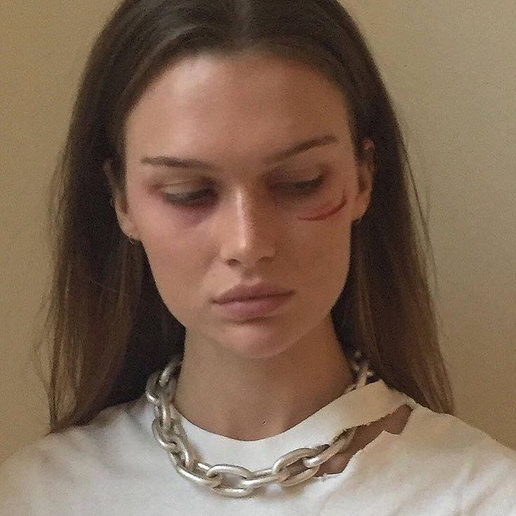 a woman wearing a white shirt with a chain around her neck and eyeliners