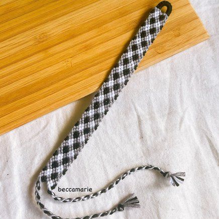 a black and white checkered tie laying on top of a wooden table next to a cutting board