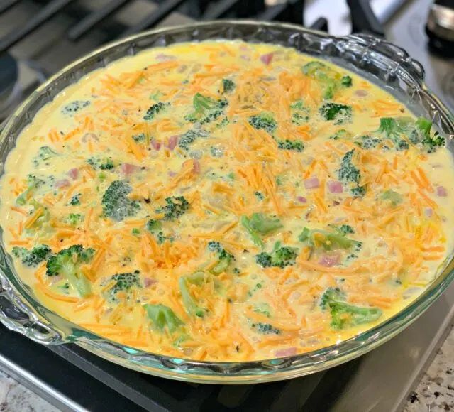 a casserole dish with cheese and broccoli in it on the stove