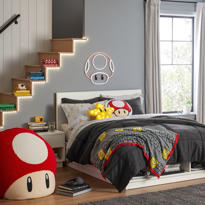 a bed room with a neatly made bed and a mario mouse pillow