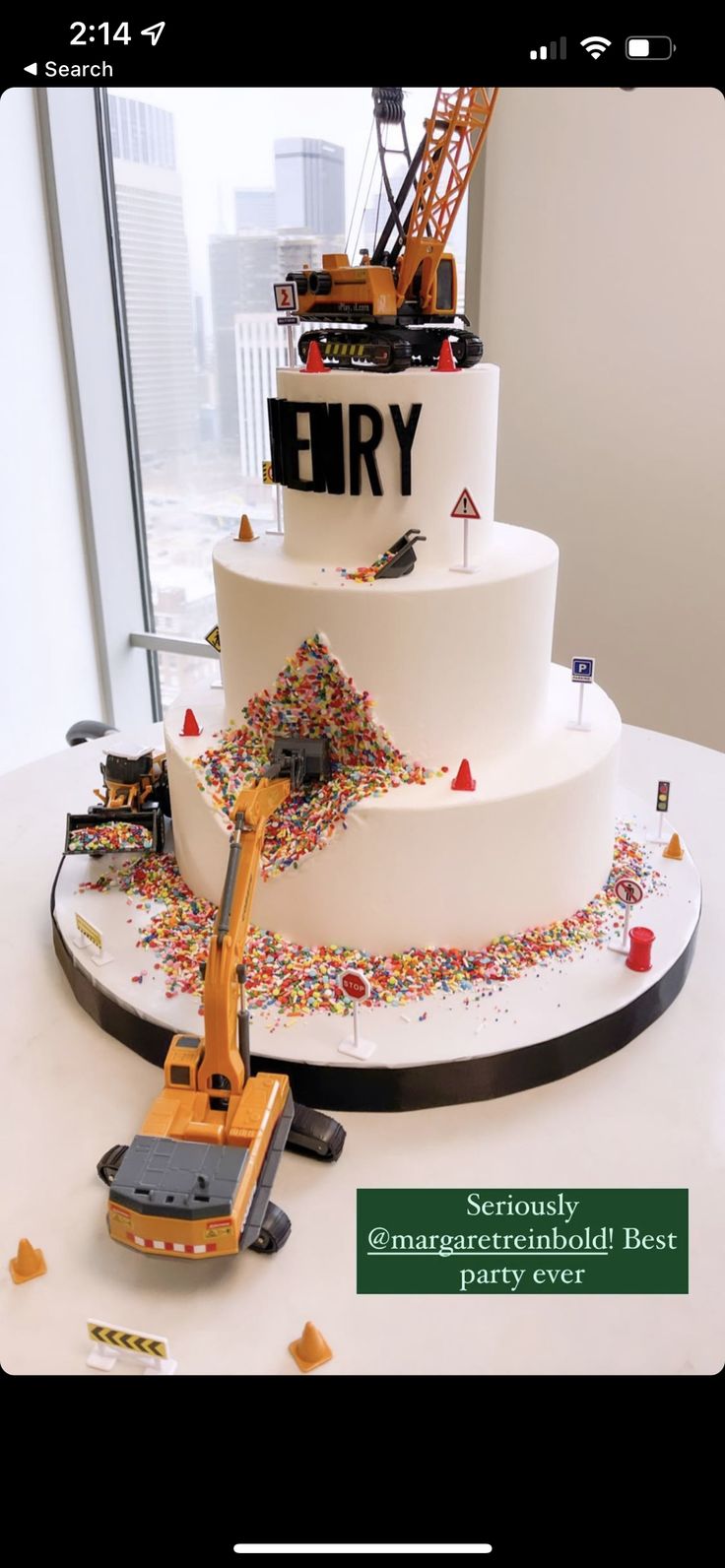 a three tiered cake with construction equipment on top and confetti sprinkles all over it