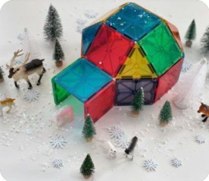 a colorful building surrounded by small trees and snow covered ground with animals in the background