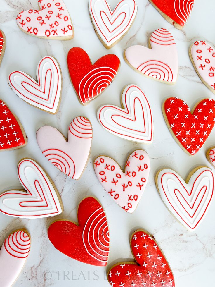 heart shaped cookies are arranged on a marble countertop with red and white icing