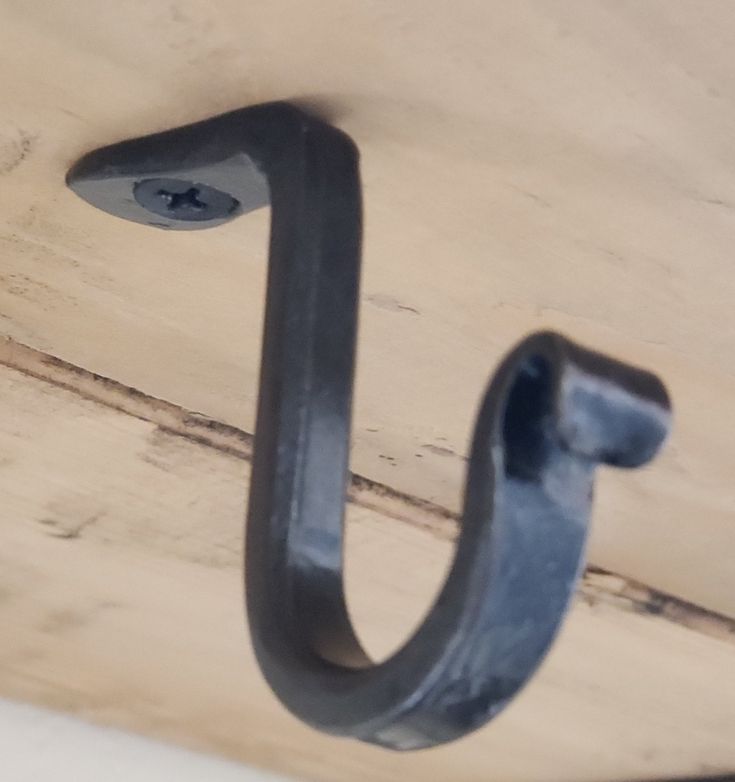 a metal hook is hanging on the side of a wooden wall