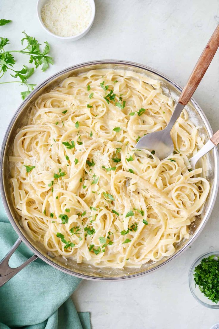 a pan filled with pasta and parsley on top of a table