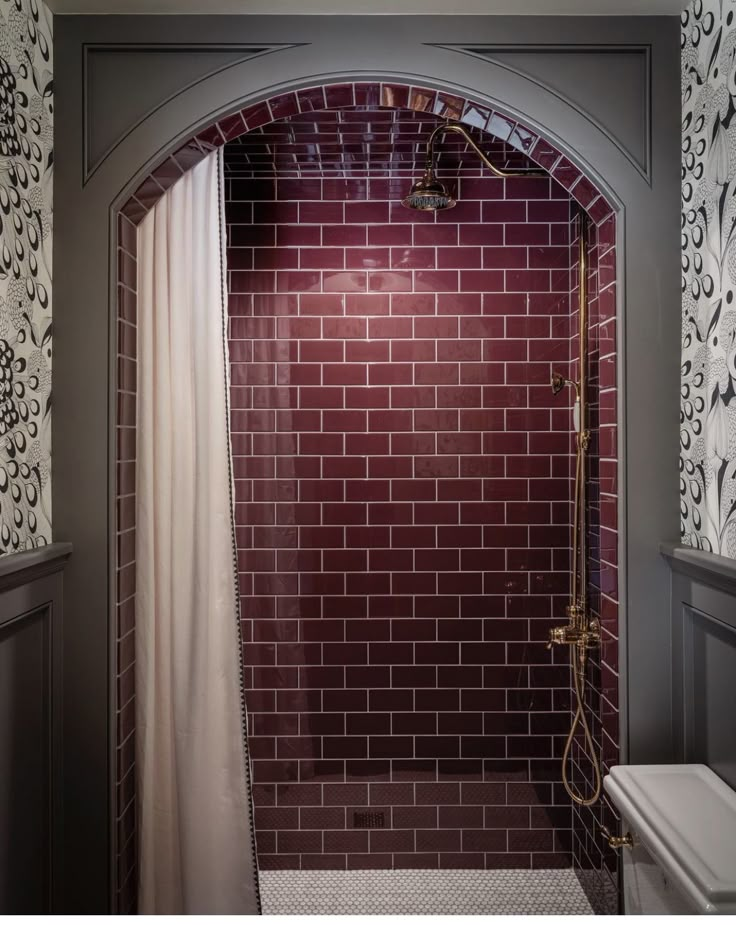 a bathroom with a red brick wall and white shower curtain