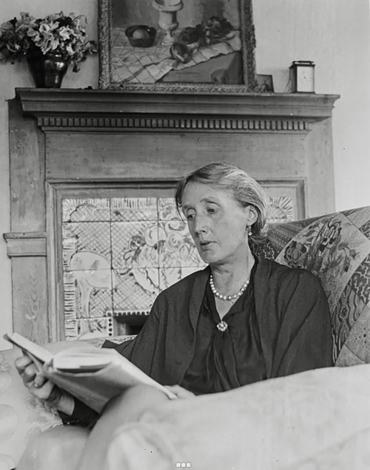 an old woman sitting on a couch reading a book