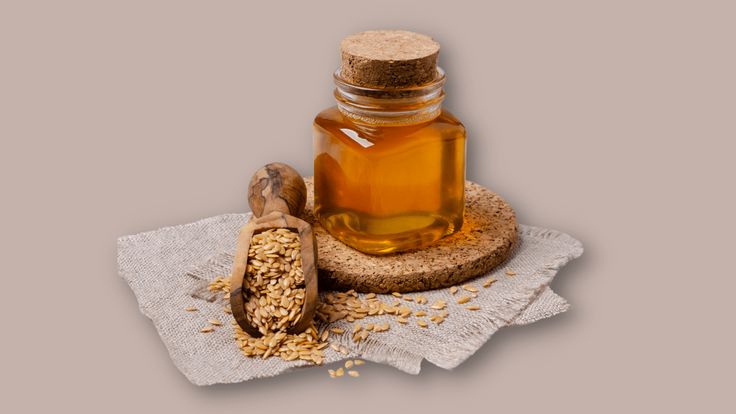 a glass bottle filled with honey sitting on top of a table next to a wooden spoon