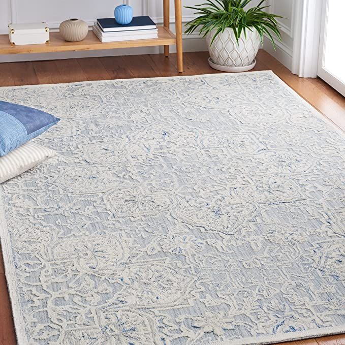 a blue and white rug on the floor in a living room with a plant next to it