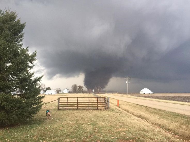 a large black cloud is in the sky over a farm