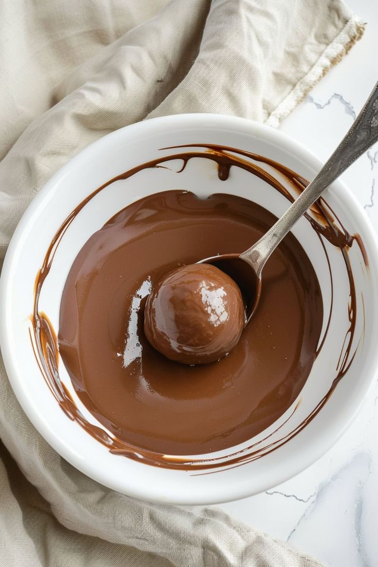 a white bowl filled with melted chocolate and a spoon