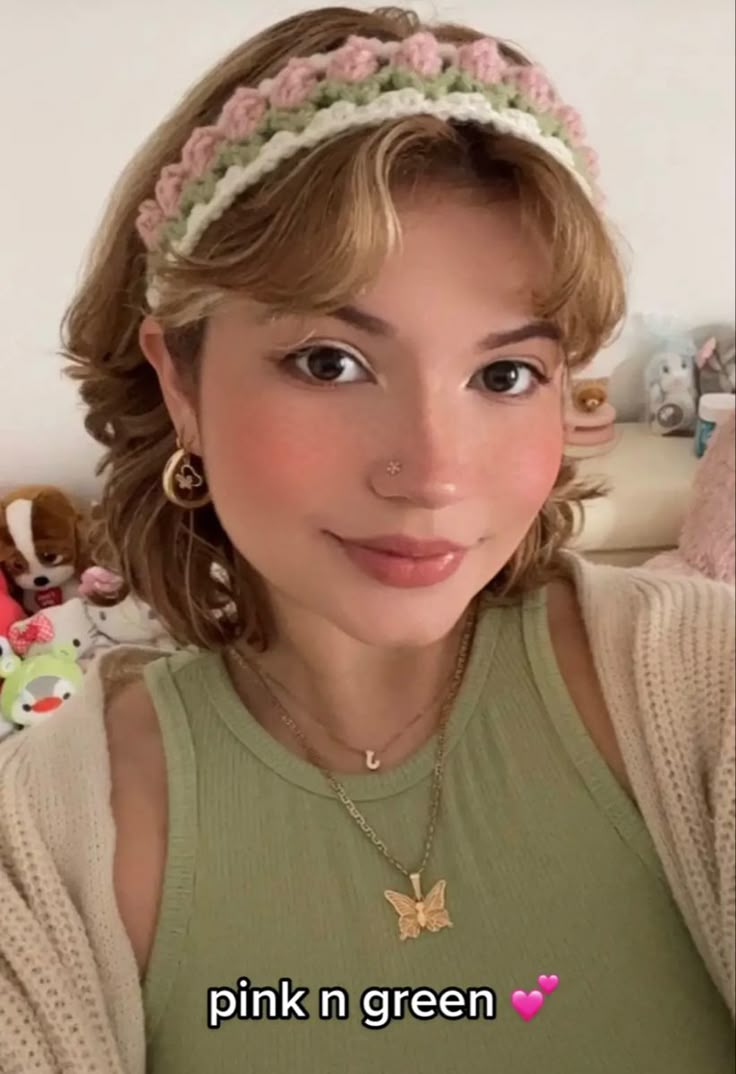 a woman with blonde hair wearing a pink and green flowered headband in front of her face