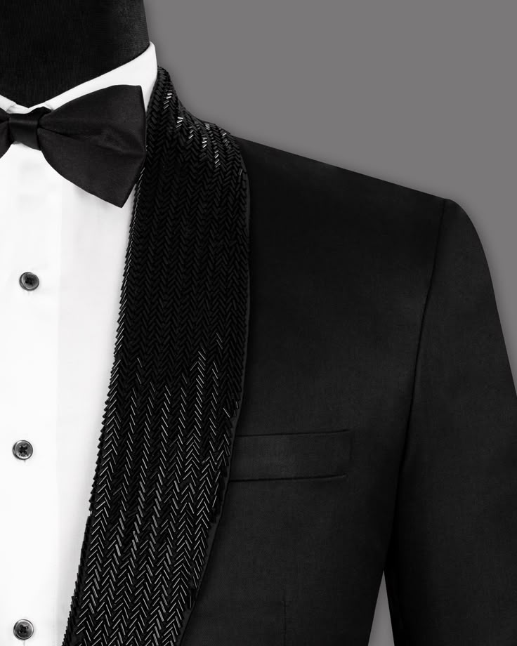 a man in a tuxedo is wearing a black and white bow tie on his lapel