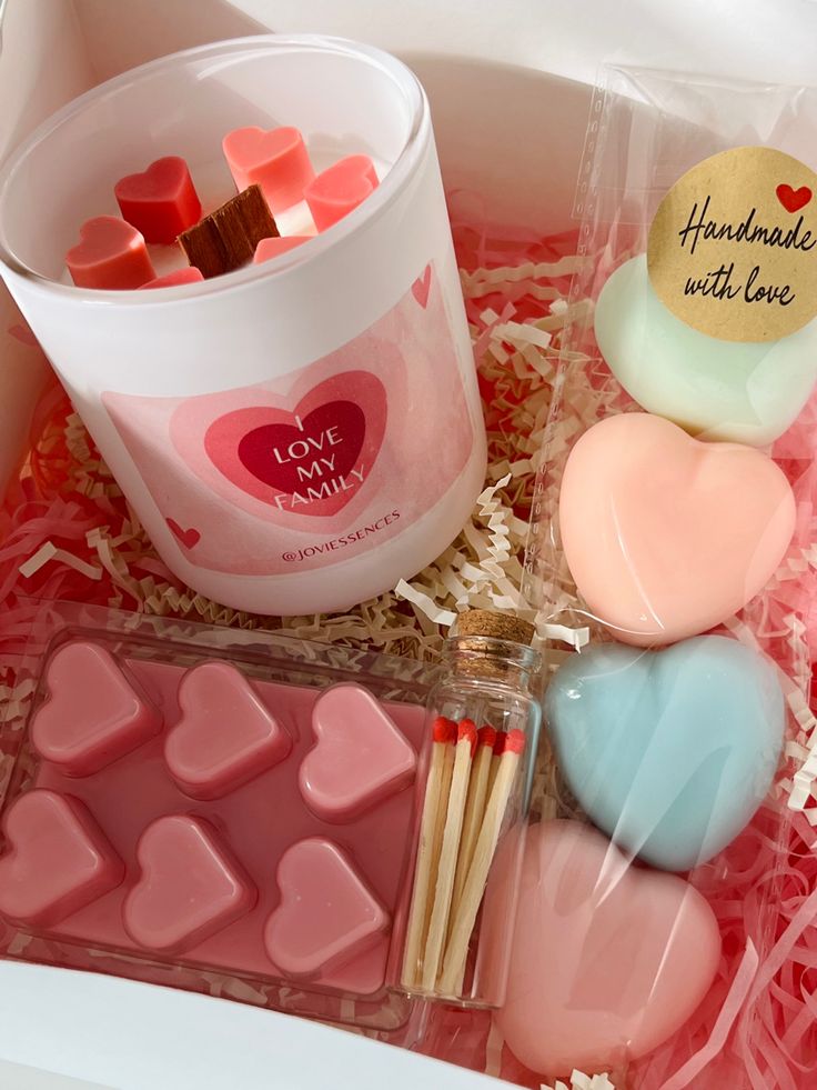 some heart shaped candies are in a plastic container and on the table is a cup of marshmallows