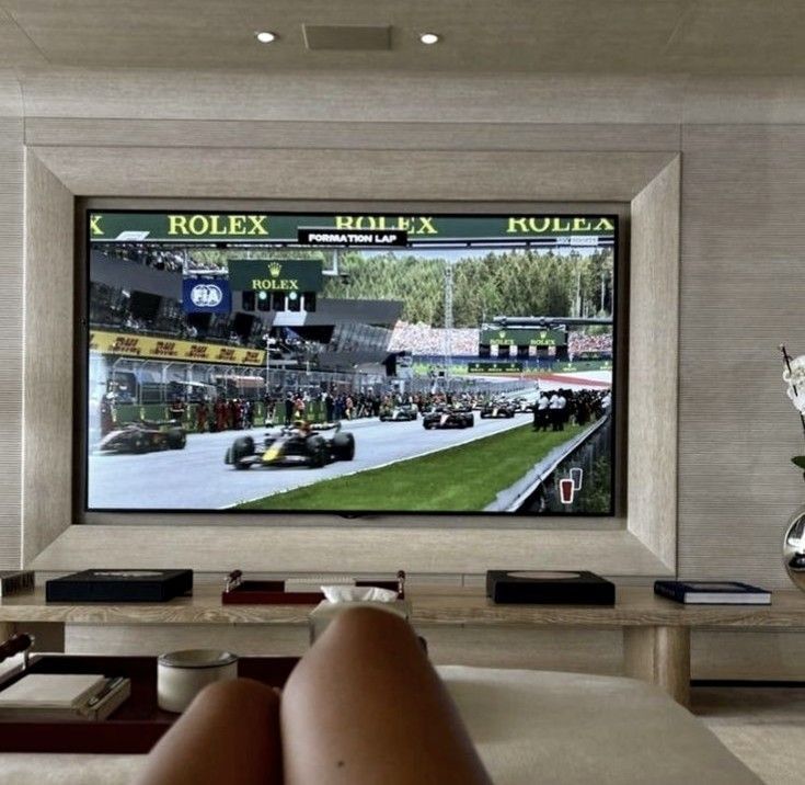 a person laying down in front of a tv with a race on it's screen