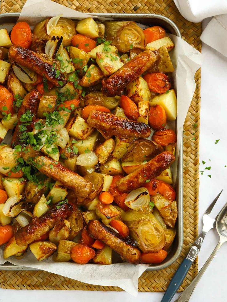 a tray filled with meat and vegetables on top of a table next to utensils