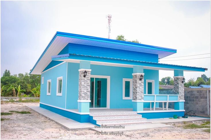 a small blue house sitting on top of a dirt field