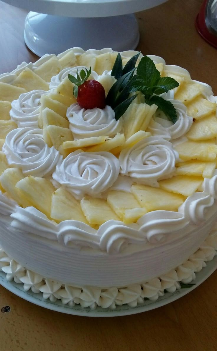 a cake with white icing and strawberries on top is sitting on a table