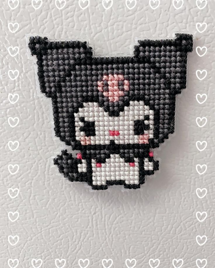 a black and white cat with pink bow on it's head is hanging from the wall