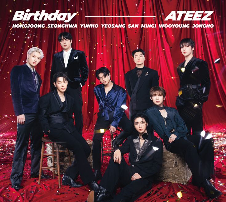 a group of young men sitting on top of a red chair in front of a red curtain