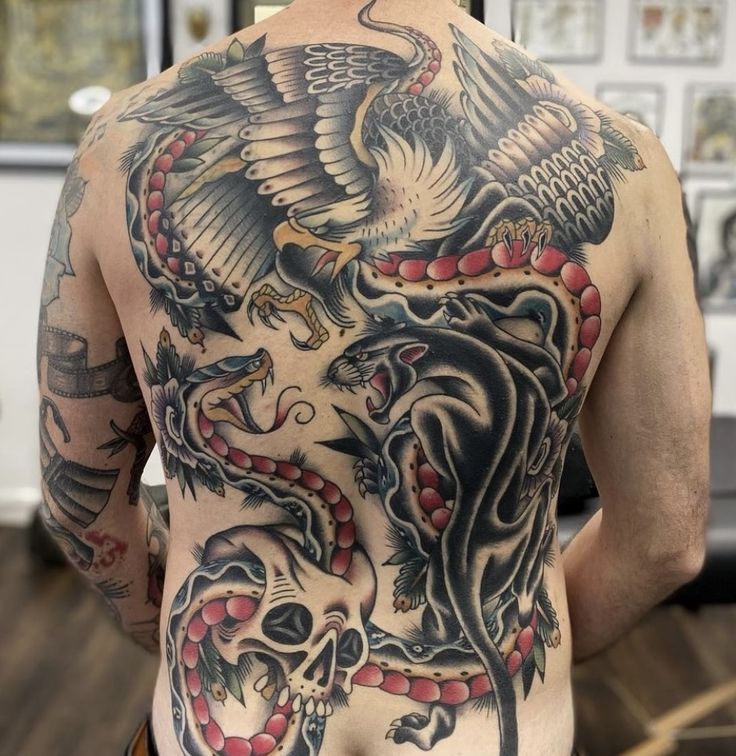 the back of a man's tattoo with an eagle and snake on his chest