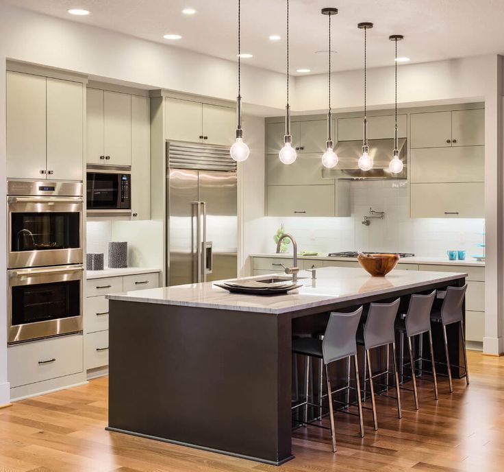 a large kitchen with an island in the middle and lots of lights hanging from the ceiling