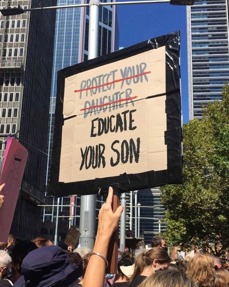 a group of people holding up signs in front of tall buildings with words written on them