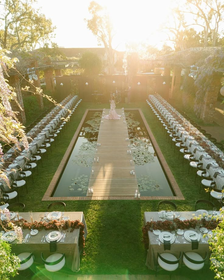 an aerial view of a long table set up in the middle of a formal garden