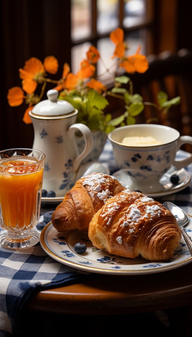 two croissants are sitting on a table with orange juice