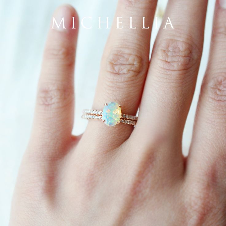 a woman's hand with a ring on it that has an opal in the middle