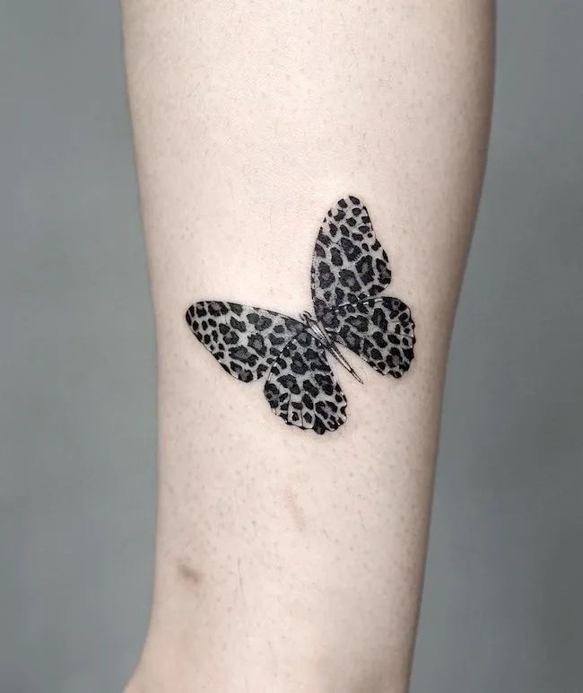 a small black and white butterfly tattoo on the right side of the calf's leg